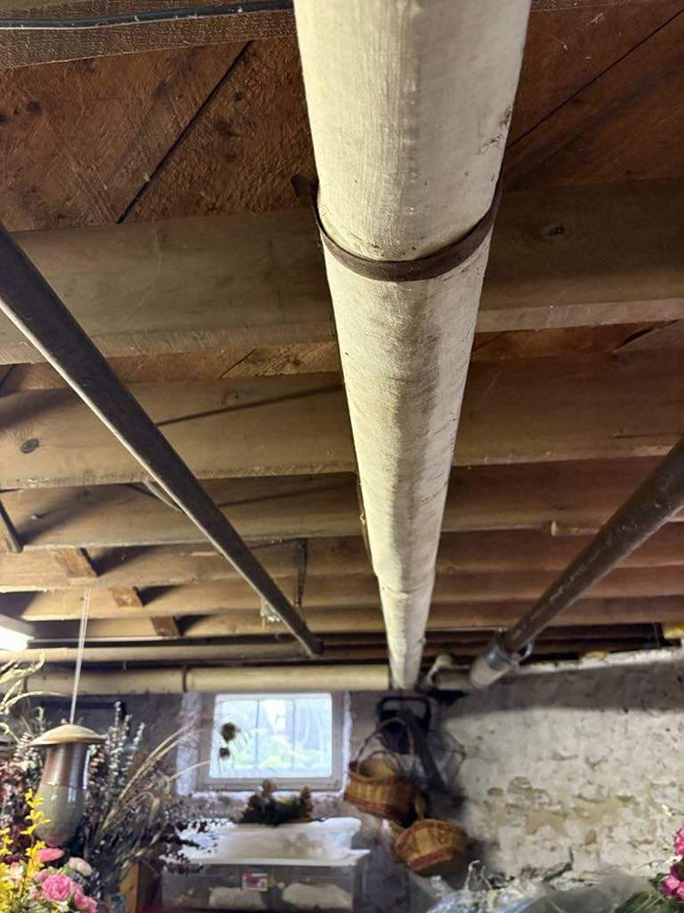 Photo of asbestos on a water pipe in a basement.